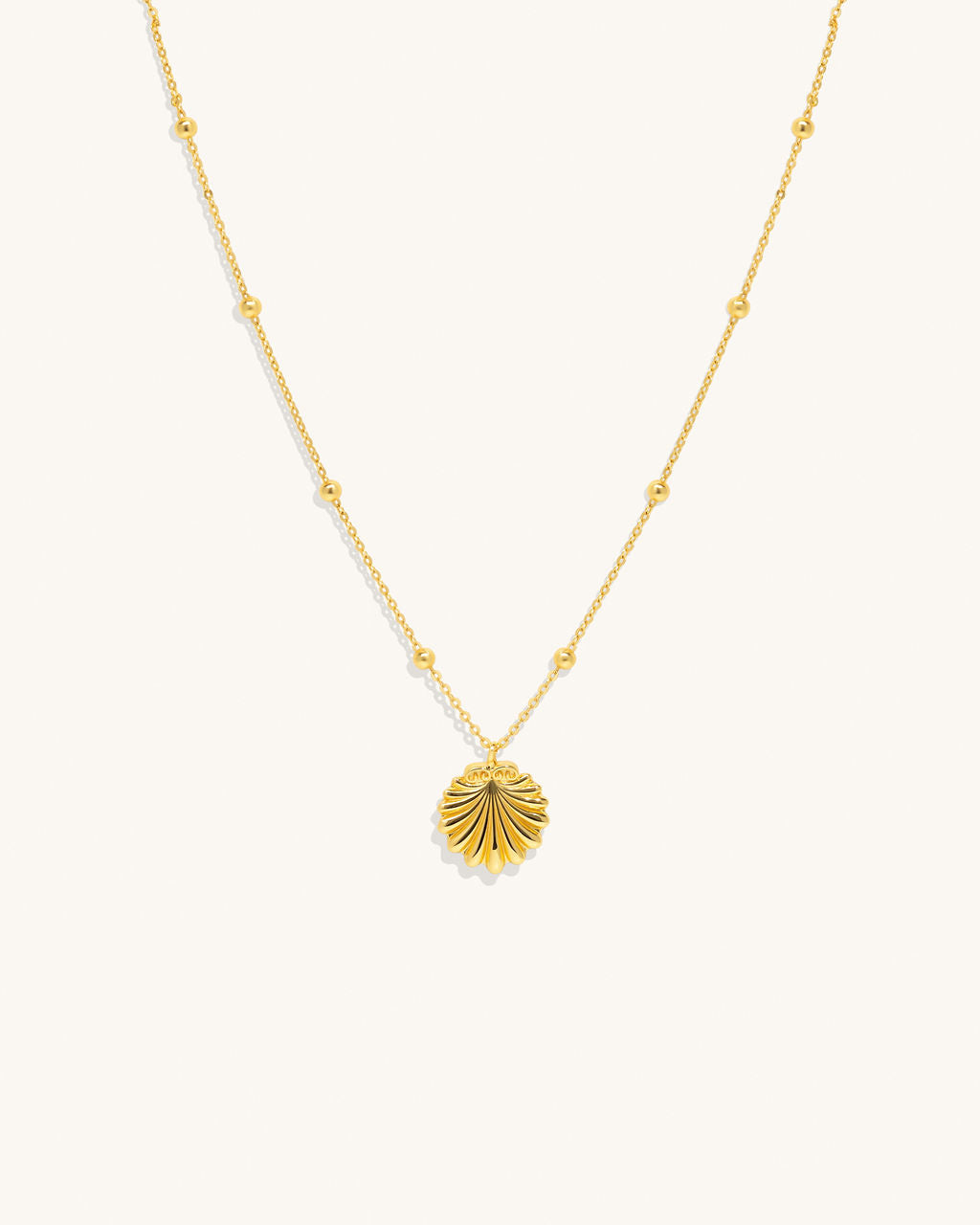 gold chain necklace with round gold pieces along the chain and a gold shell like pendant woman jewelry