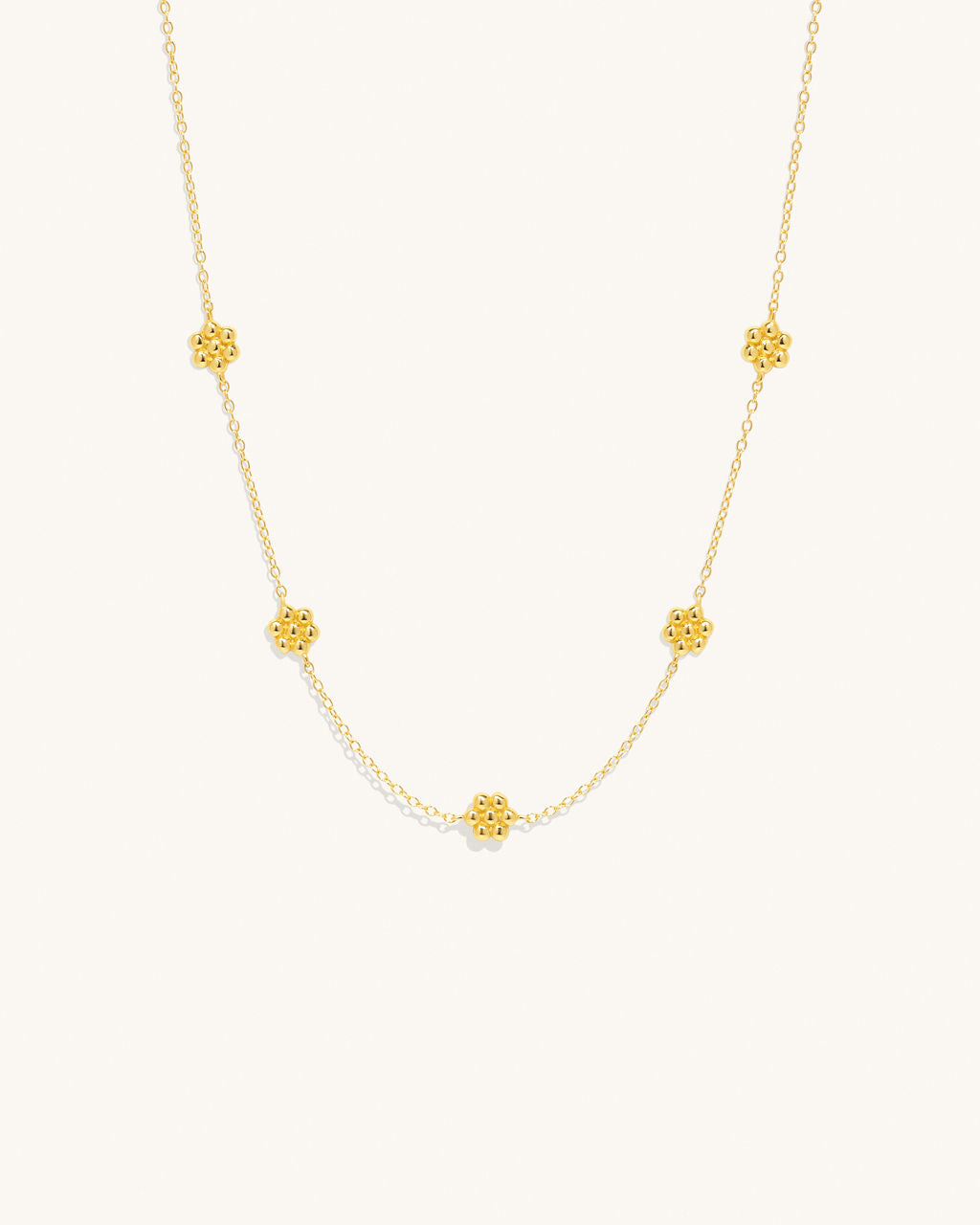 gold chain necklace with small flower pendants along the chain womans jewelry