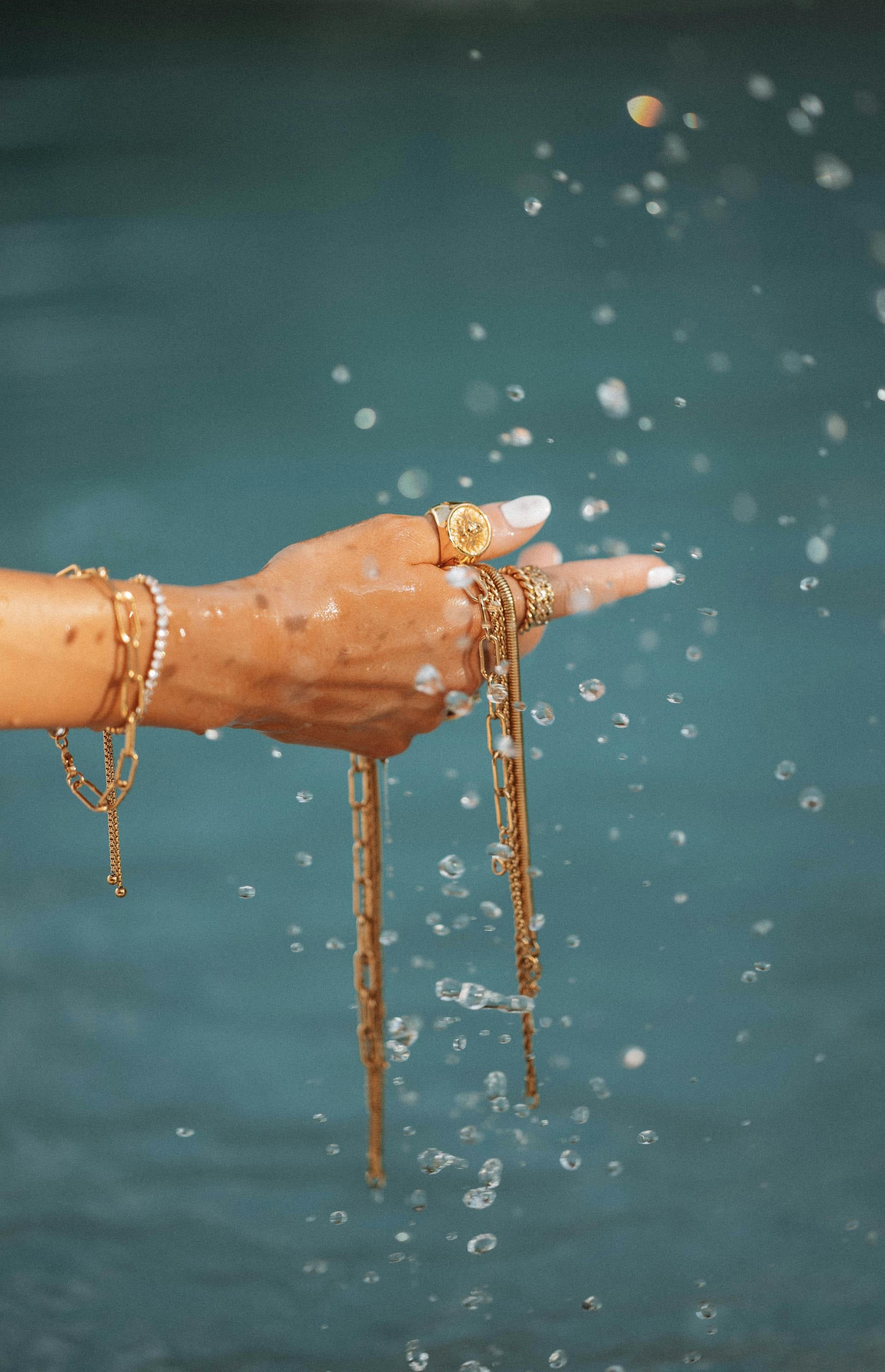 Gold chain jewelry submerged in water with bubbles — illustrating the water resistance of gold vermeil